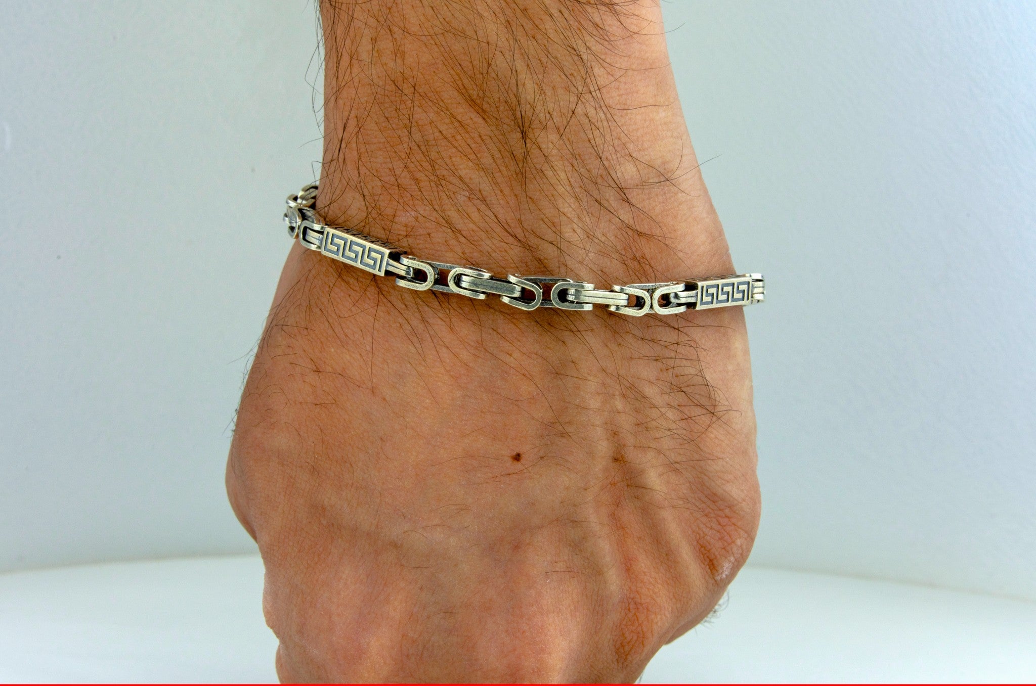 Greek Key Link Bracelet  by Miraura Jewels on a person's wrist against a white background
