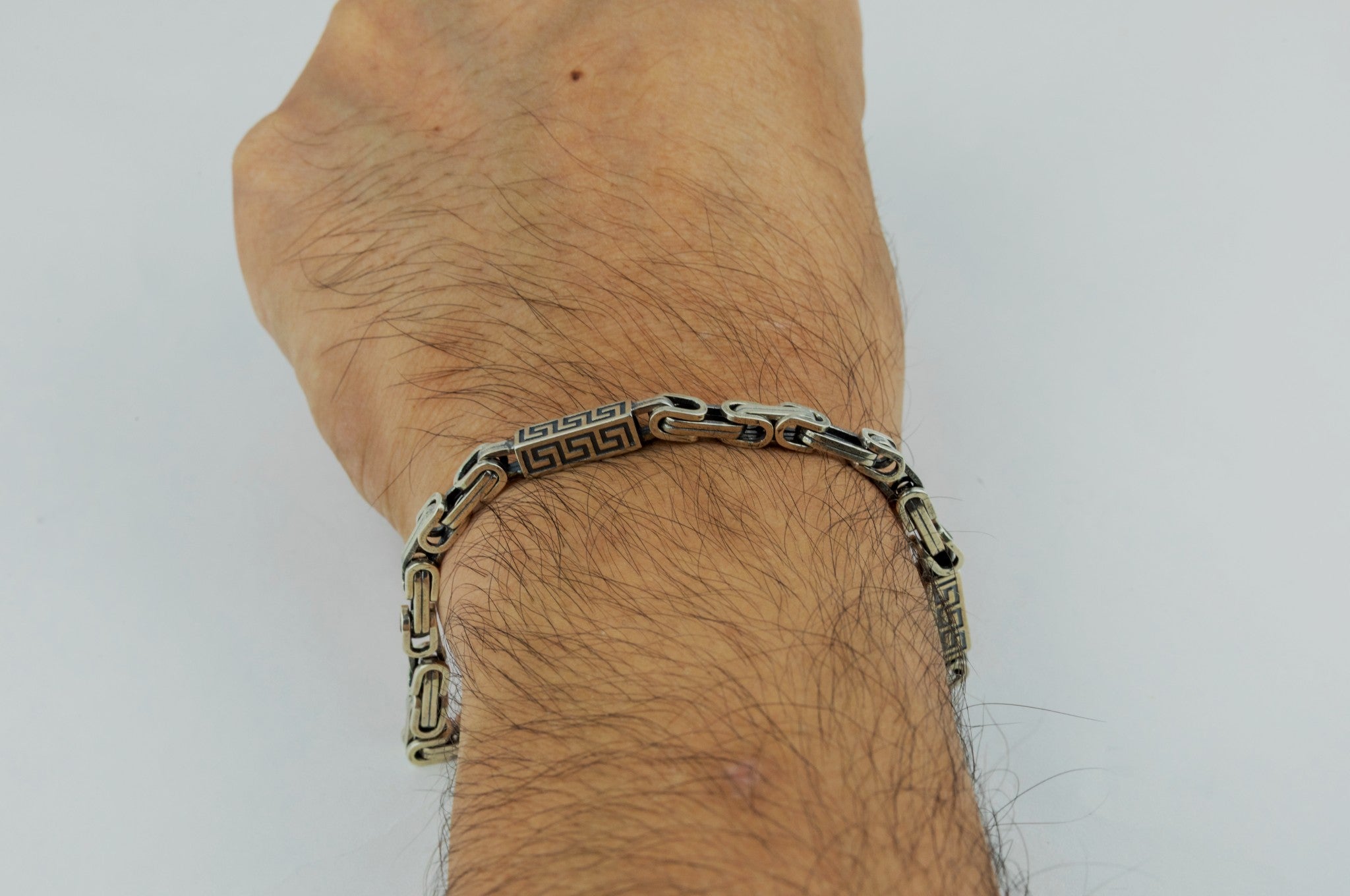 Greek Key Link Bracelet  by Miraura Jewels on a person's wrist against a white background