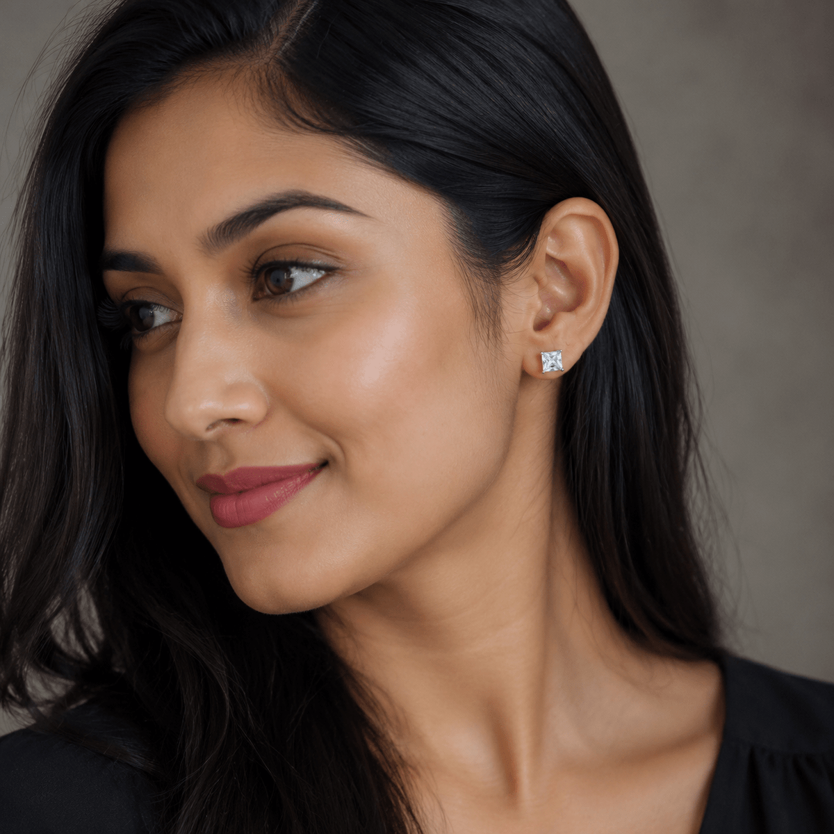A close-up portrait of a woman wearing 925 Silver Princess-Cut Solitaire Studs | Miraura Jewels