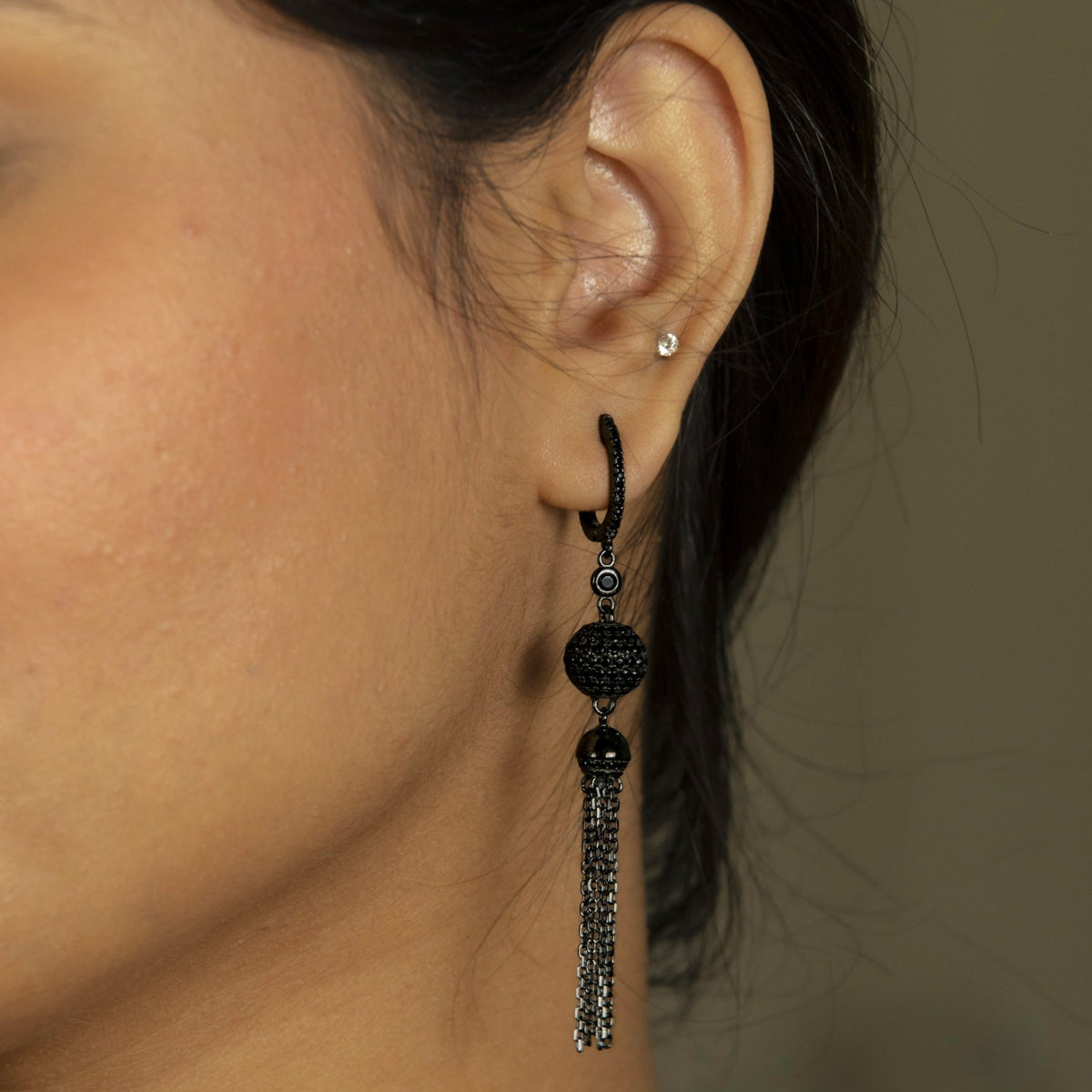 A close-up of a girl's ear wearing a long, dangling 925 Silver Black Rhodium Chain Tassel Drop Earrings | Miraura Jewels