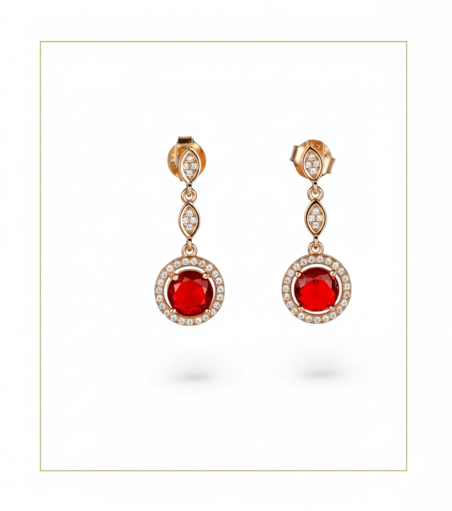 Pair of earrings with red gemstones and rose gold setting on a white background