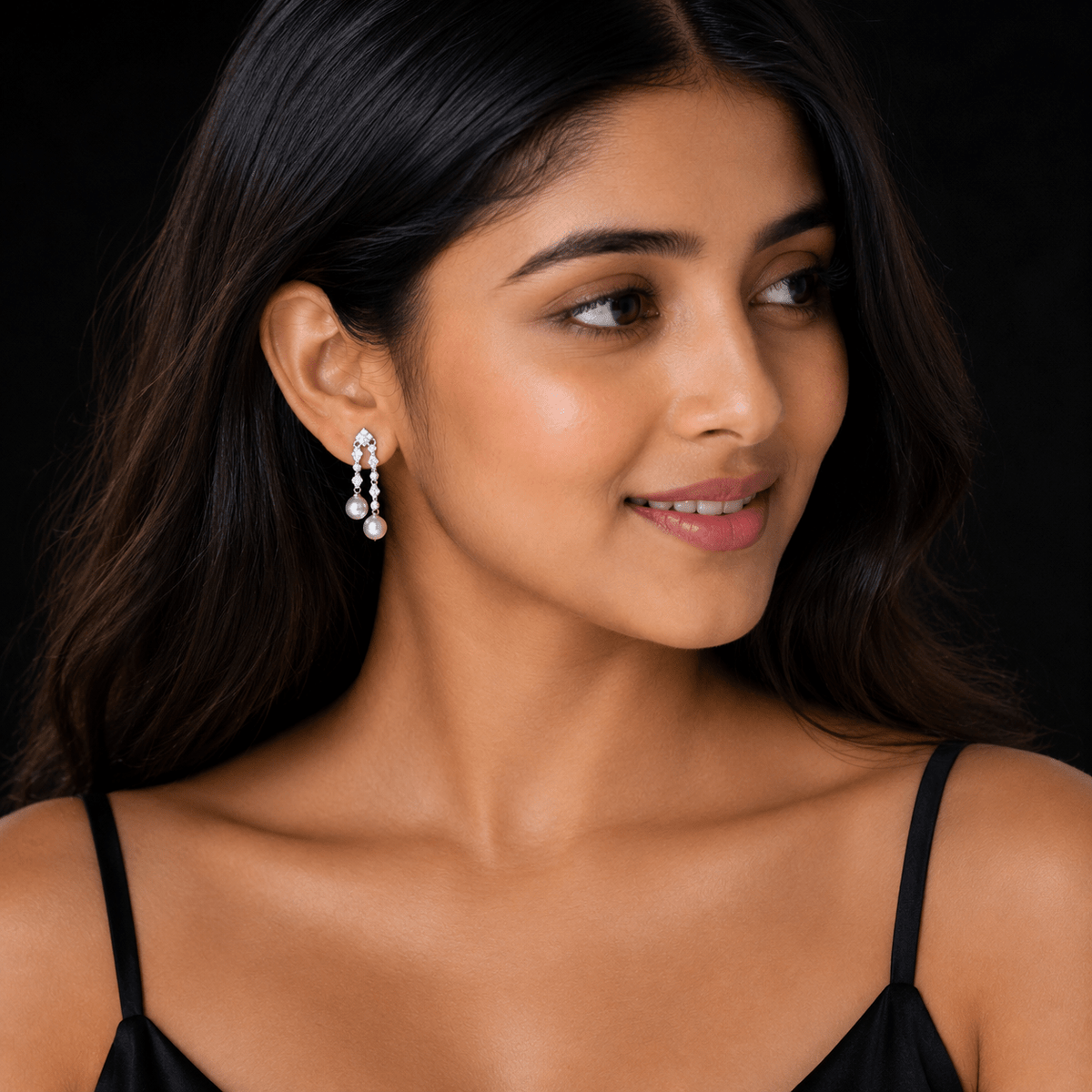 A close-up portrait of a woman wearing a Double Pearl Cascading Drop Earrings | 925 Silver by Miraura Jewels against a solid black background.