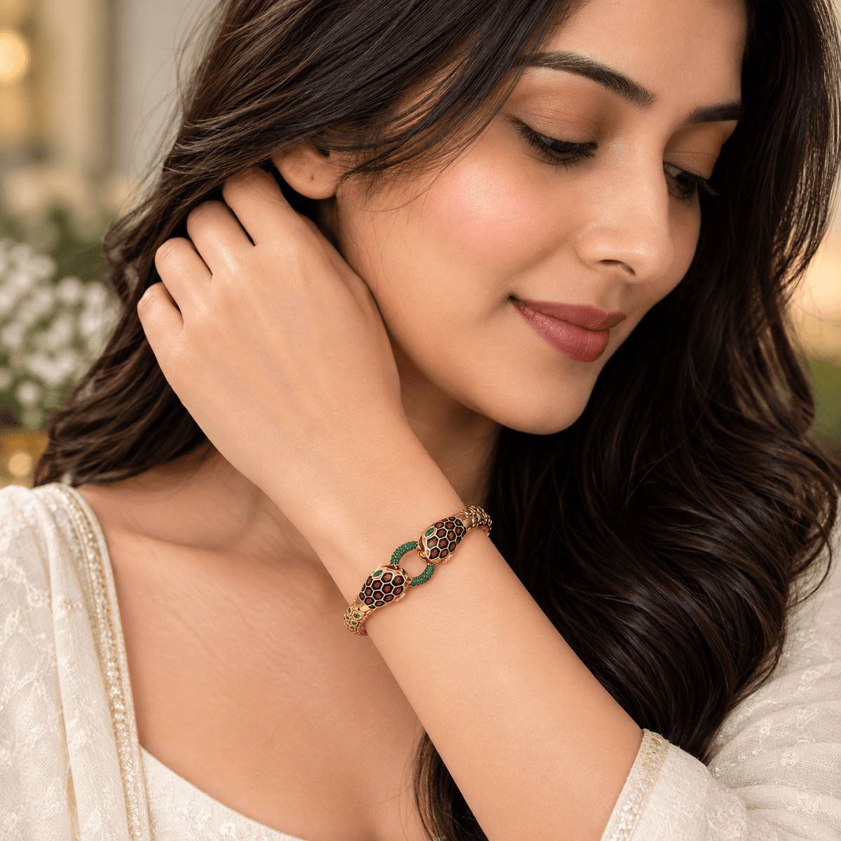 A young  charming girl wearing a Double Headed Serpent Bangle - by Miraura Jewels. rose gold-plated chain bracelet adorned with green and red enamel links, shown in a close-up lifestyle shot.