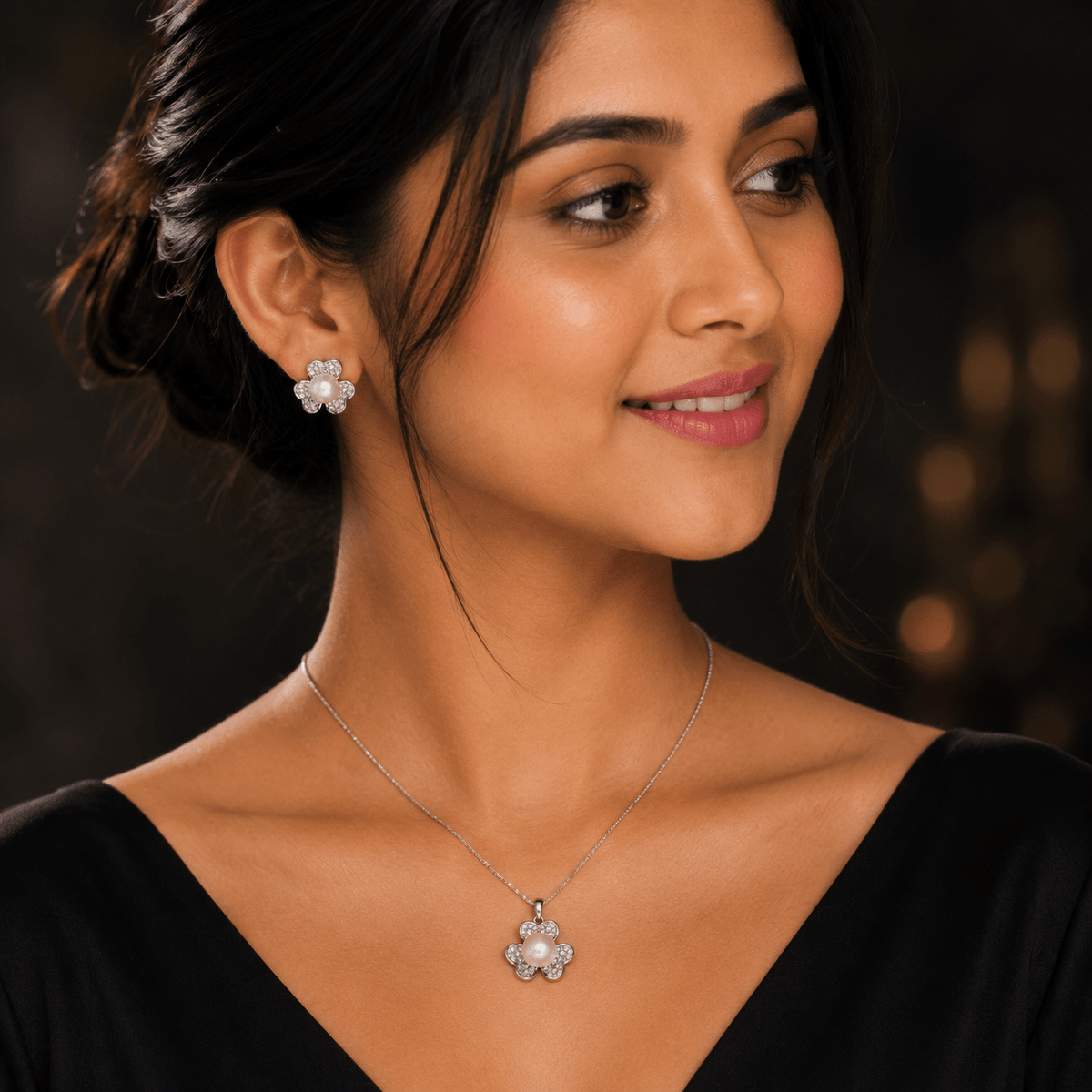 A beautiful indian young girl wearing Pearl Clover Pendant & Stud 3pc Set by Miraura Jewels, Jaipur. A 925 silver, flower-shaped pendant necklace and matching stud earring, shown in a close-up portrait against a dark blurred background.