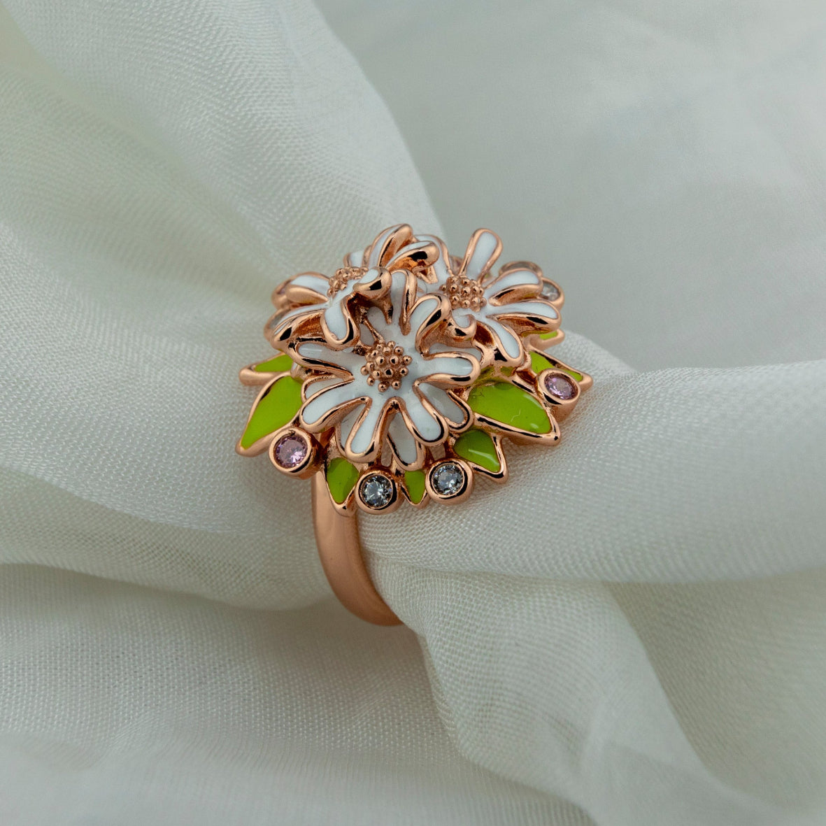 Decorative ring by Miraura with floral design on a white fabric background
