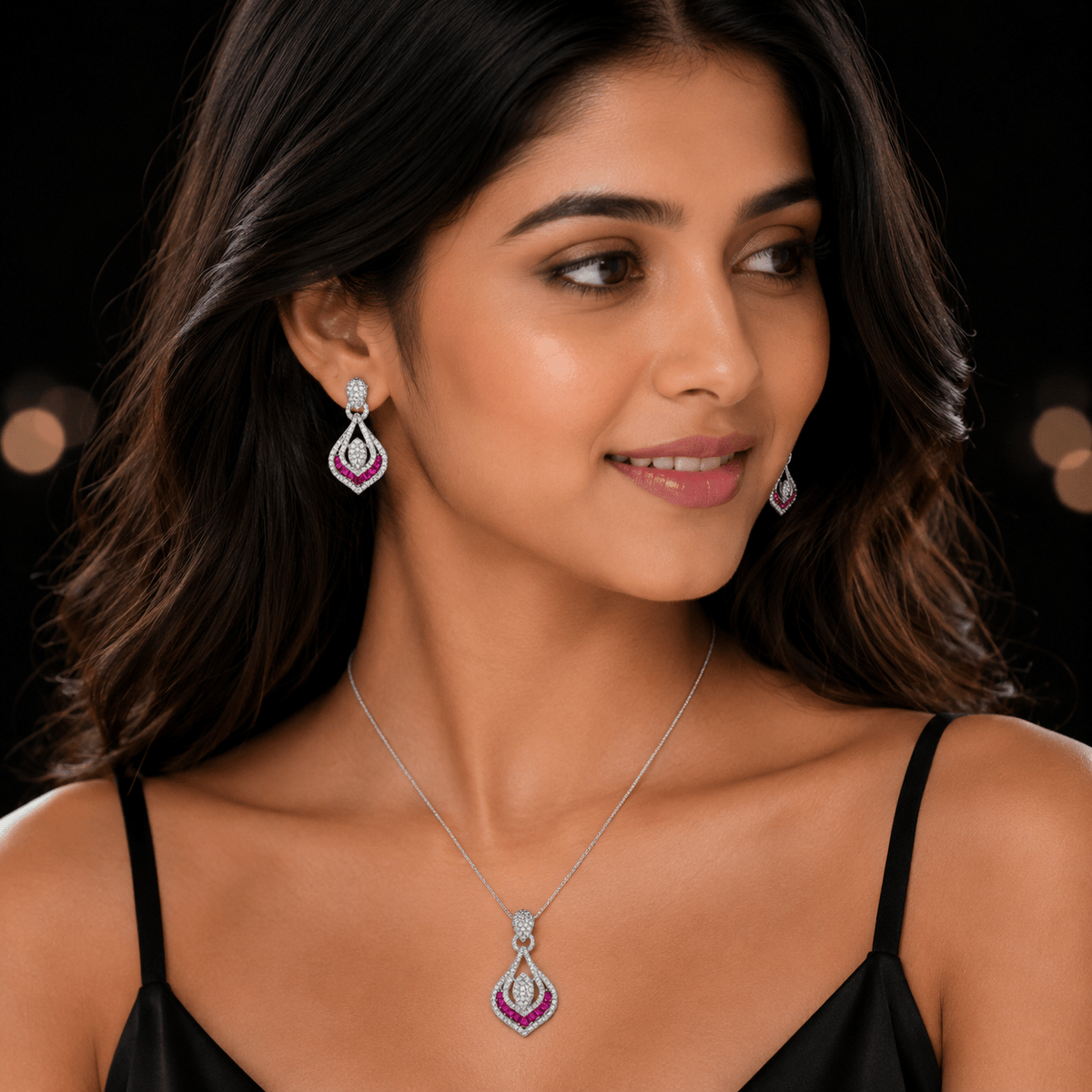 A woman wearing a matching Ruby Zircon Teardrop Pendant & Stud Set, by Miraura Jewels,Jaipur shown in a close-up portrait against a dark background with soft bokeh lights.