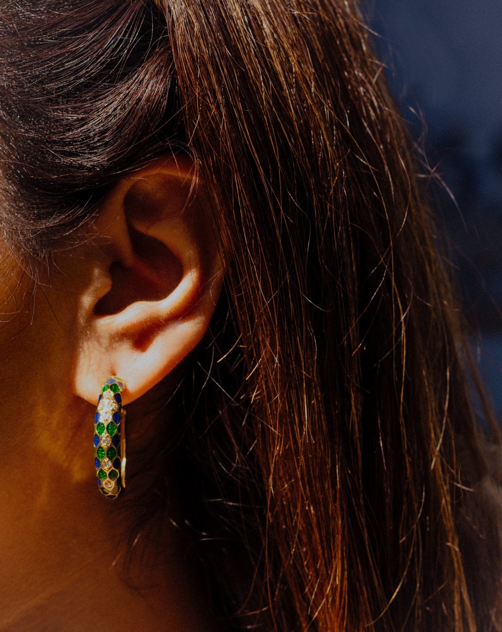 Close-up of an Girl's ear wearing a green and gold hoop earrings by Miraura Jewels.